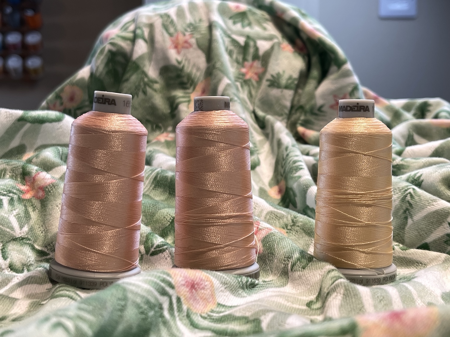 Golden thread x 3 sitting on patterned green fabric in sewing room by sewing blogger Sew Louisa