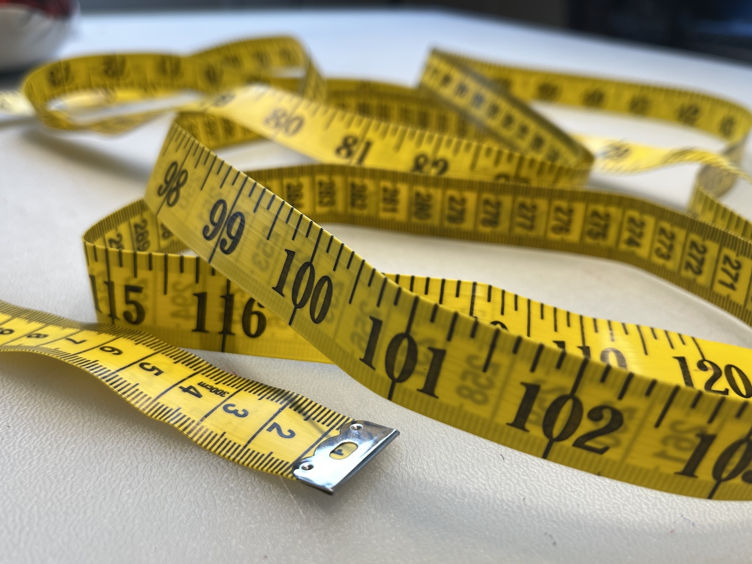 Yellow tape measure on white table in sewing room by sewing blogger Sew Louisa